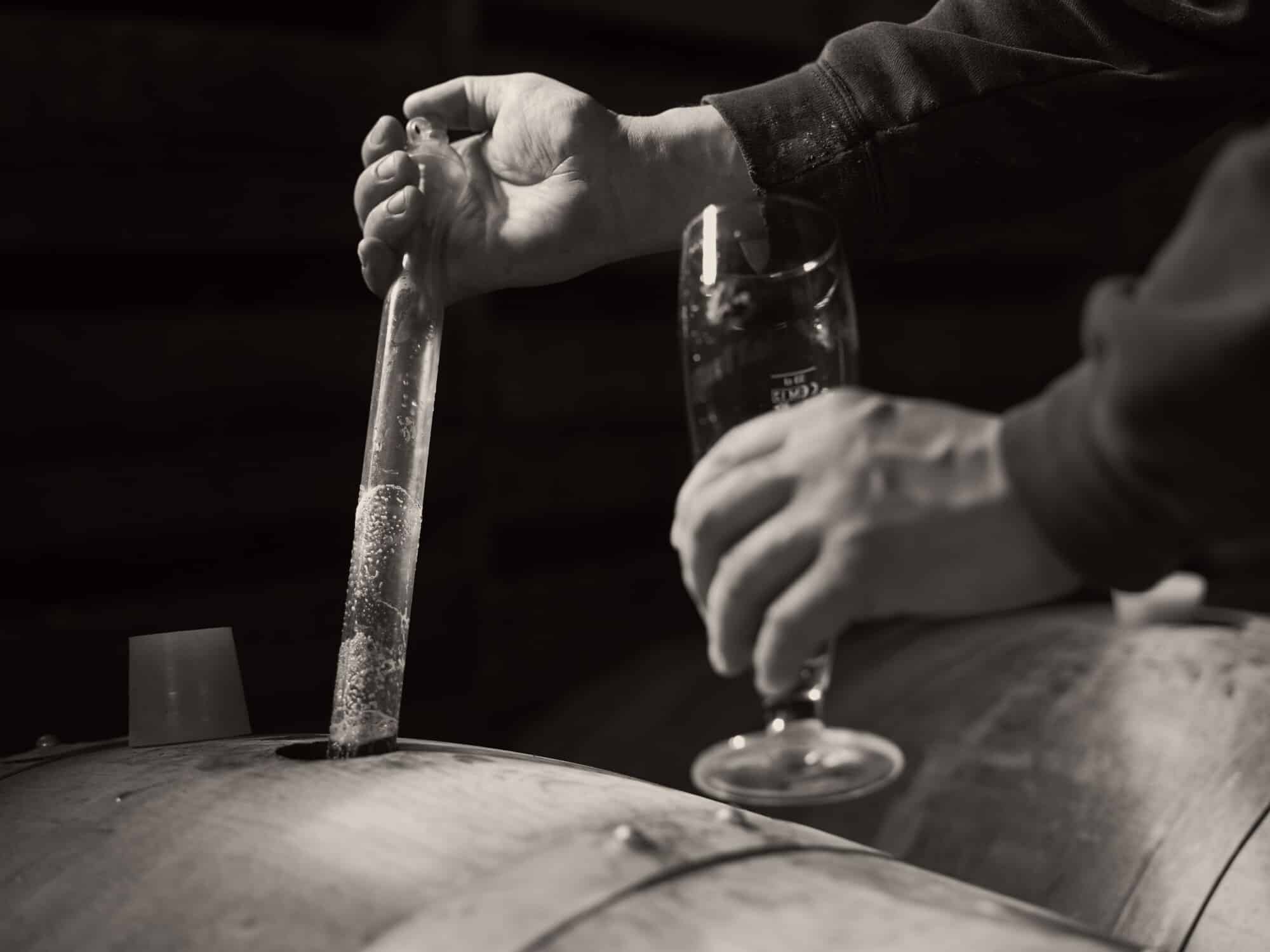 Hands grijpen fles bier vast, zwart-wit foto van ambachtelijk bierbrouwen in authentieke setting