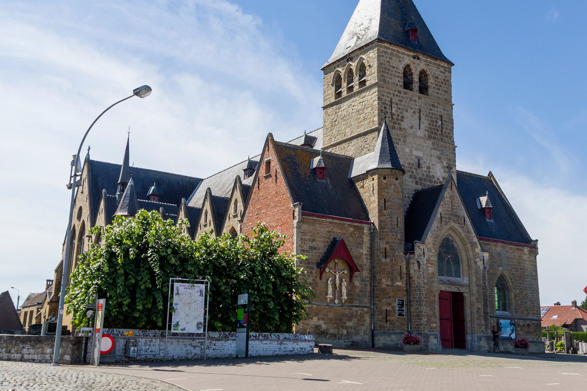 Historische kerk met stenen toren en rode bakstenen gebouwen in Herzele, België