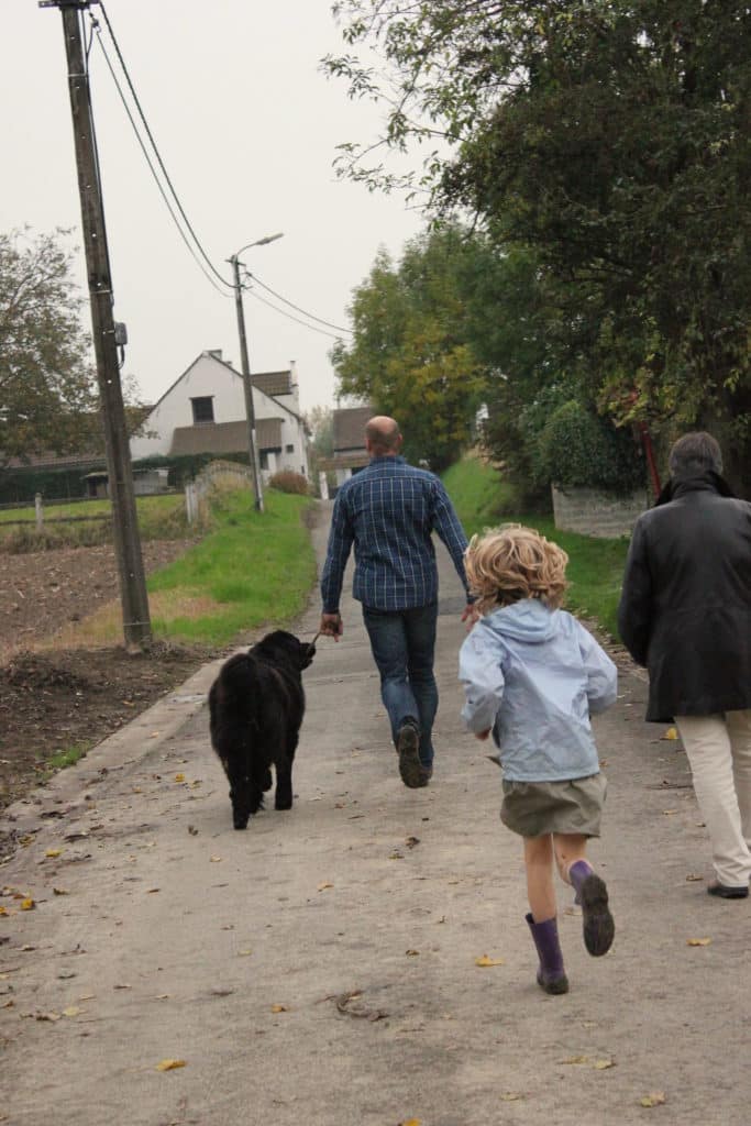 Familie wandelt met hond door rustige landelijke straat in Vlaamse Ardennen nabij vakantiewoning Eyndevelde