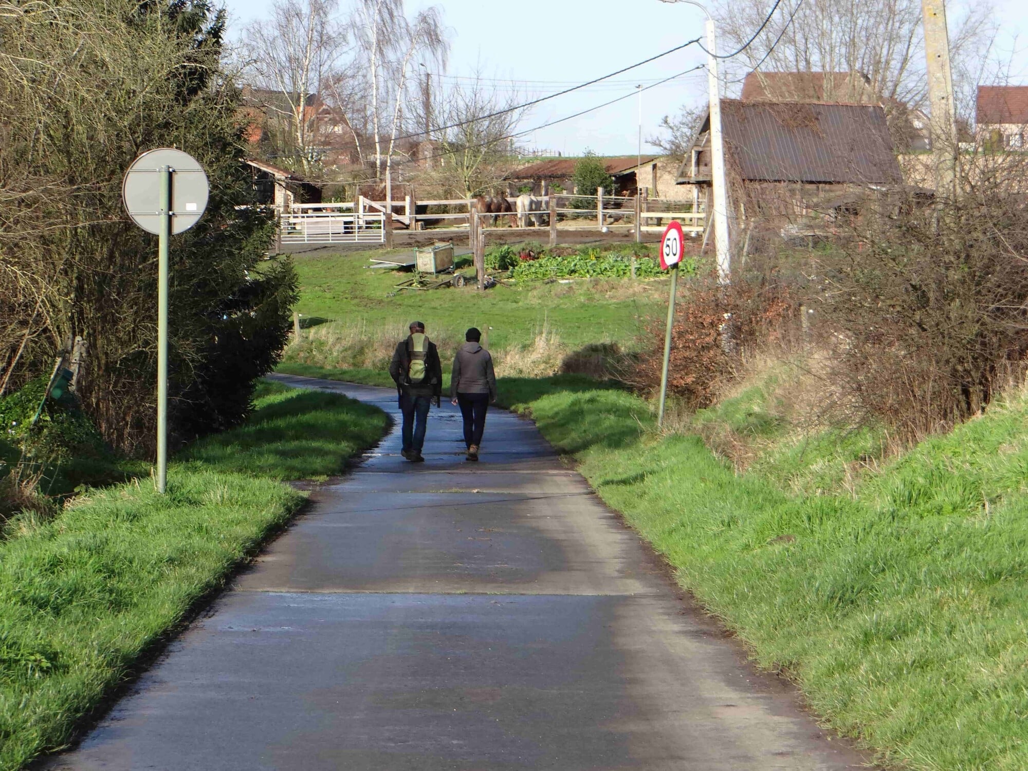 Twee personen wandelen op een landelijke weg door de Vlaamse Ardennen in Sint-Lievens-Esse