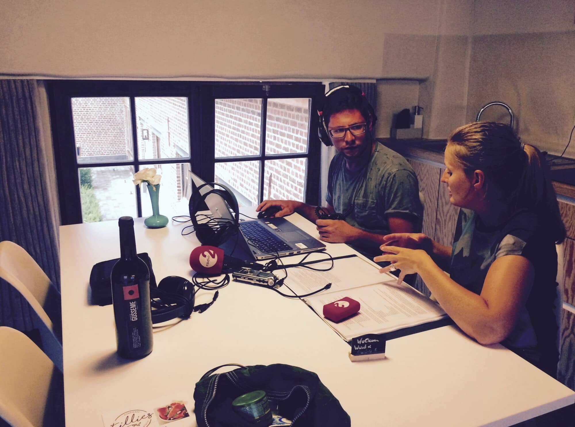 Radioreporter Ward met headset aan tafel met laptop en apparatuur tijdens Radio 2 uitzending vanuit Eyndevelde