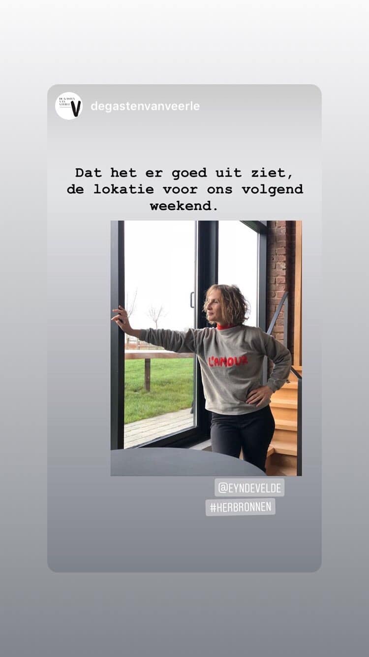 Vrouw in grijze sweater kijkt door open deur naar groene tuin, tekst over weekend locatie voor herbronnen