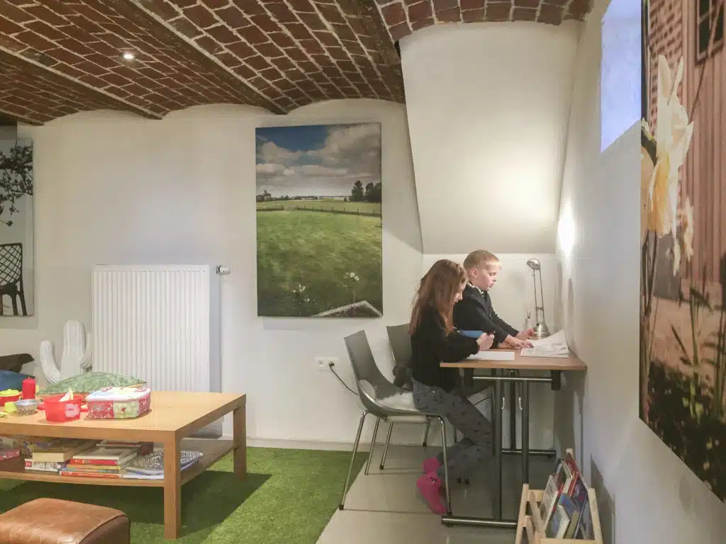 Kinderen spelen samen aan tafel in de kidscave met groene vloerbedekking en bakstenen gewelf