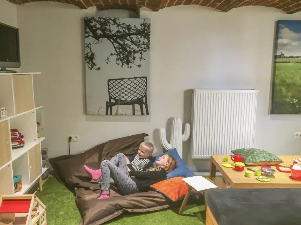 Kinderen ontspannen in de speelkamer van groepswoning Eyndevelde met speelgoed en gezellige zithoek