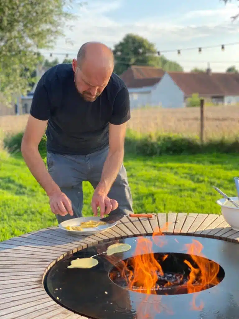 Man kookt pannenkoeken op Caspero teppanyaki-tafel met vuur in buitenomgeving van Eyndevelde vakantiewoning