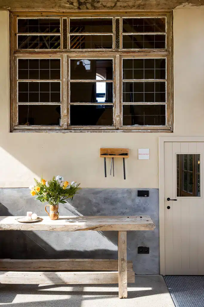 Rustieke keuken met houten tafel, gele bloemen en vintage raam in Eyndevelde vakantiewoning