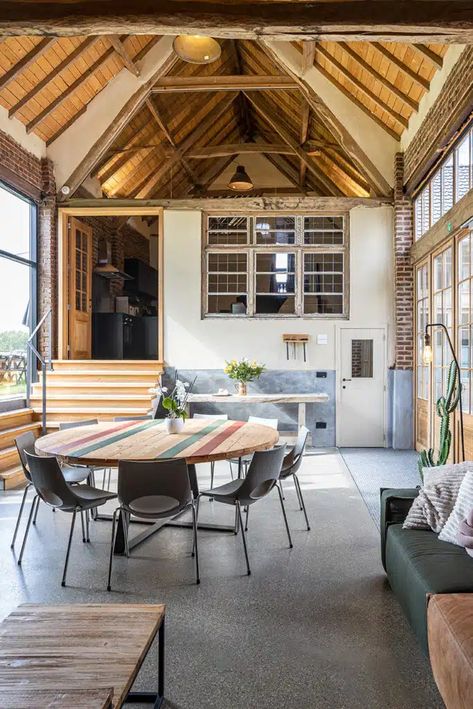 Ruime eetruimte met houten balken en ronde tafel in Eyndevelde vakantiewoning in de Vlaamse Ardennen