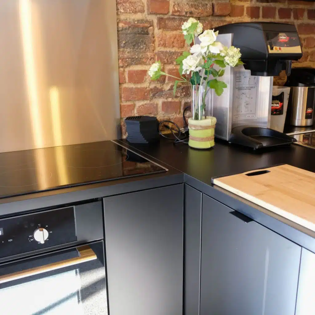 Moderne keuken met zwarte kasten, inductiekookplaat en koffiemachine in Eyndevelde vakantiewoning
