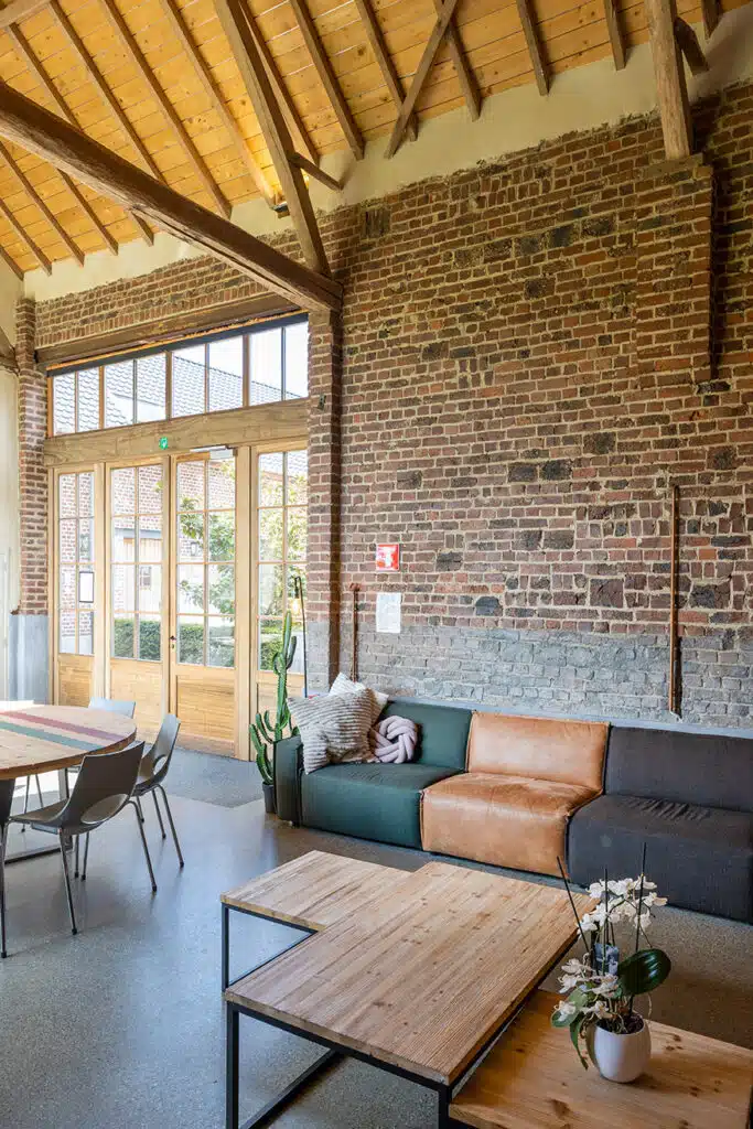 Gezellige groepsruimte Eyndevelde met bakstenen muur, moderne zithoek en houten plafondbalken