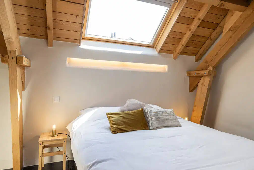 Gezellige slaapkamer met houten balken, skylight en comfortabel bed in vakantiewoning Eyndevelde