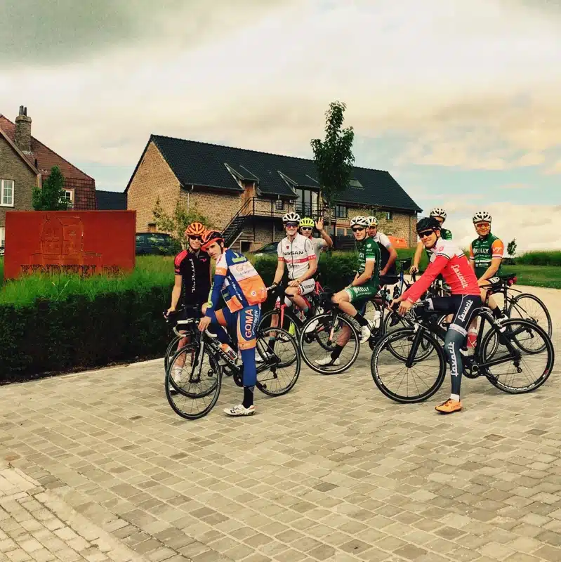 Groep wielrenners in kleurrijke wielershirts met fietsen op kasseien bij vakantiewoning Eyndevelde