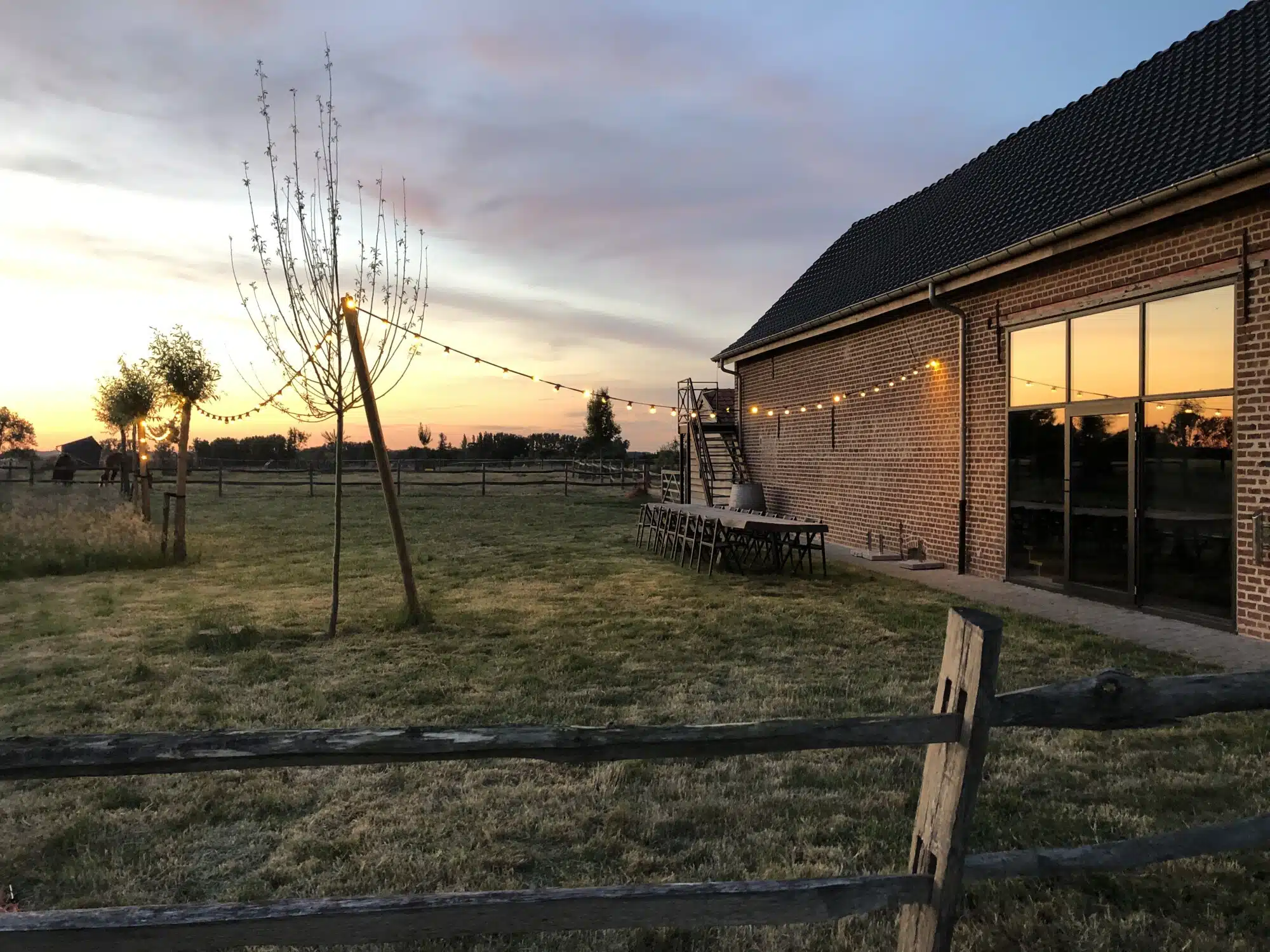 Eyndevelde vakantiewoning in Vlaamse Ardennen bij zonsondergang met groene velden en gezellige verlichting
