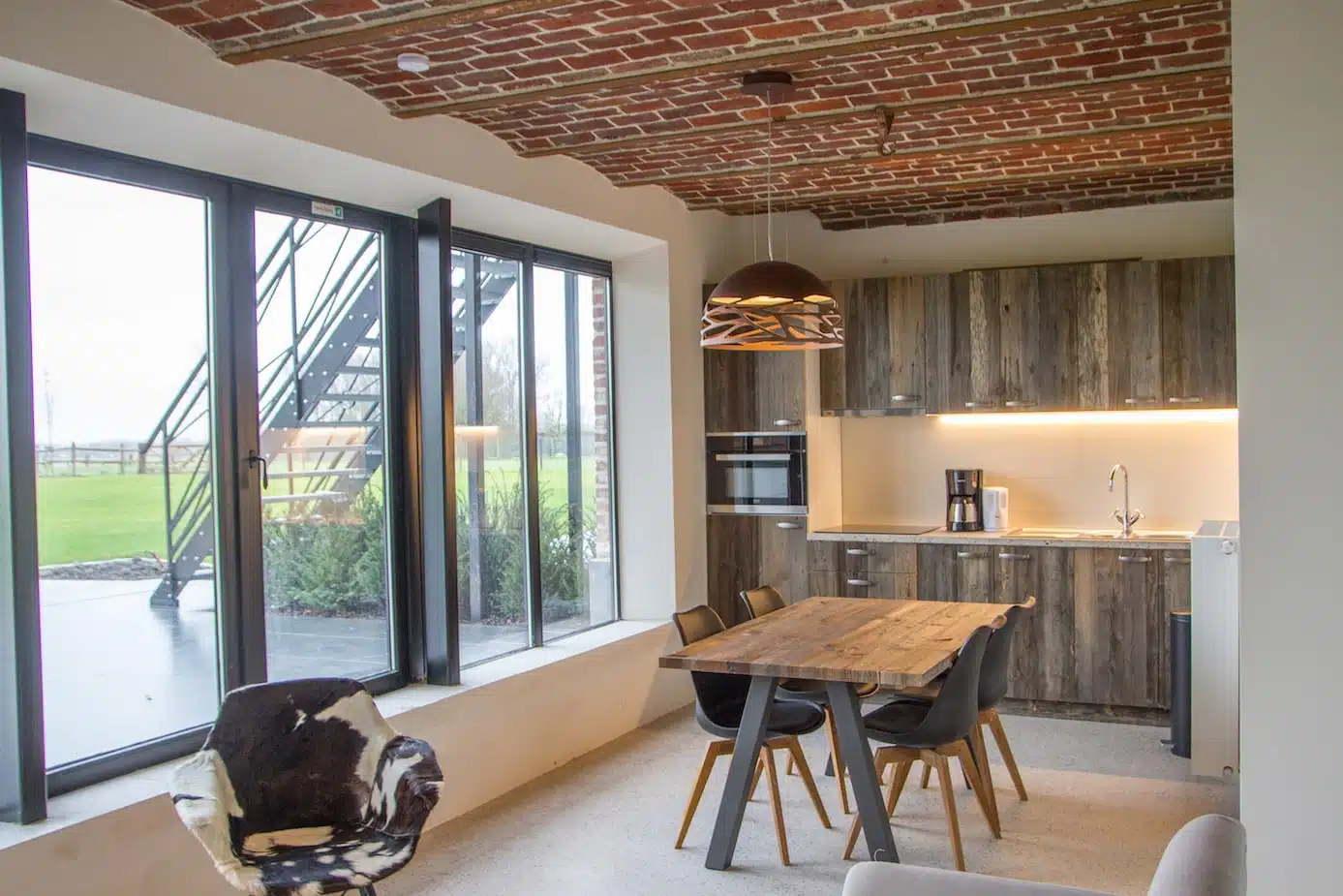 Moderne open keuken met houten kasten en eettafel in luxe vakantiewoning Eyndevelde, Vlaamse Ardennen