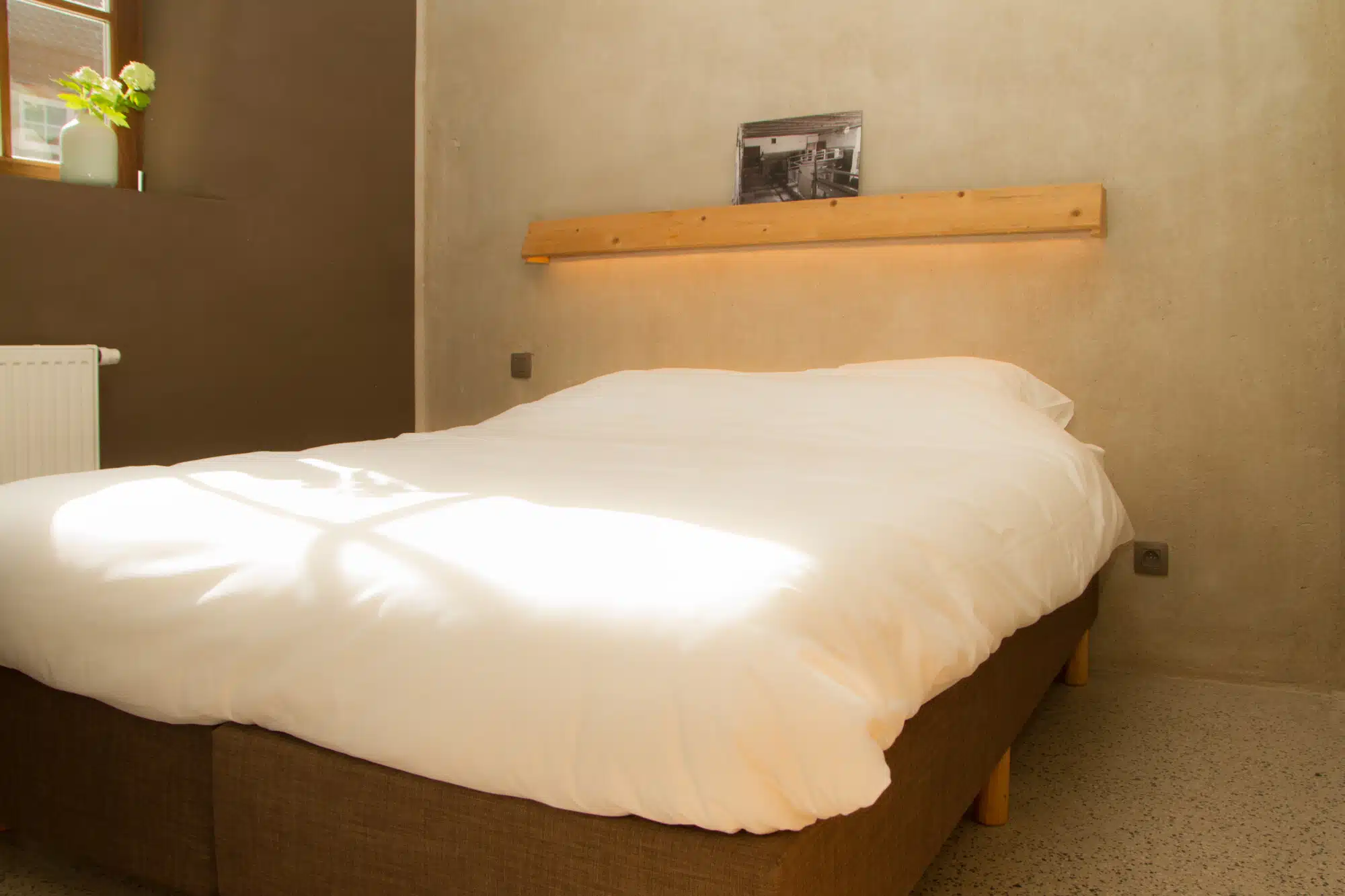 Moderne slaapkamer met wit beddengoed en houten bed bij Eyndevelde leven en beleven
