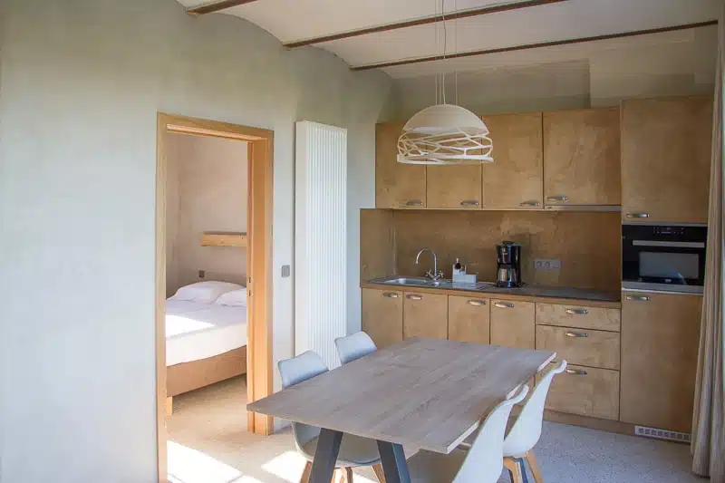 Moderne keuken met eettafel en zicht op slaapkamer in vakantiewoning Eyndevelde Vlaamse Ardennen