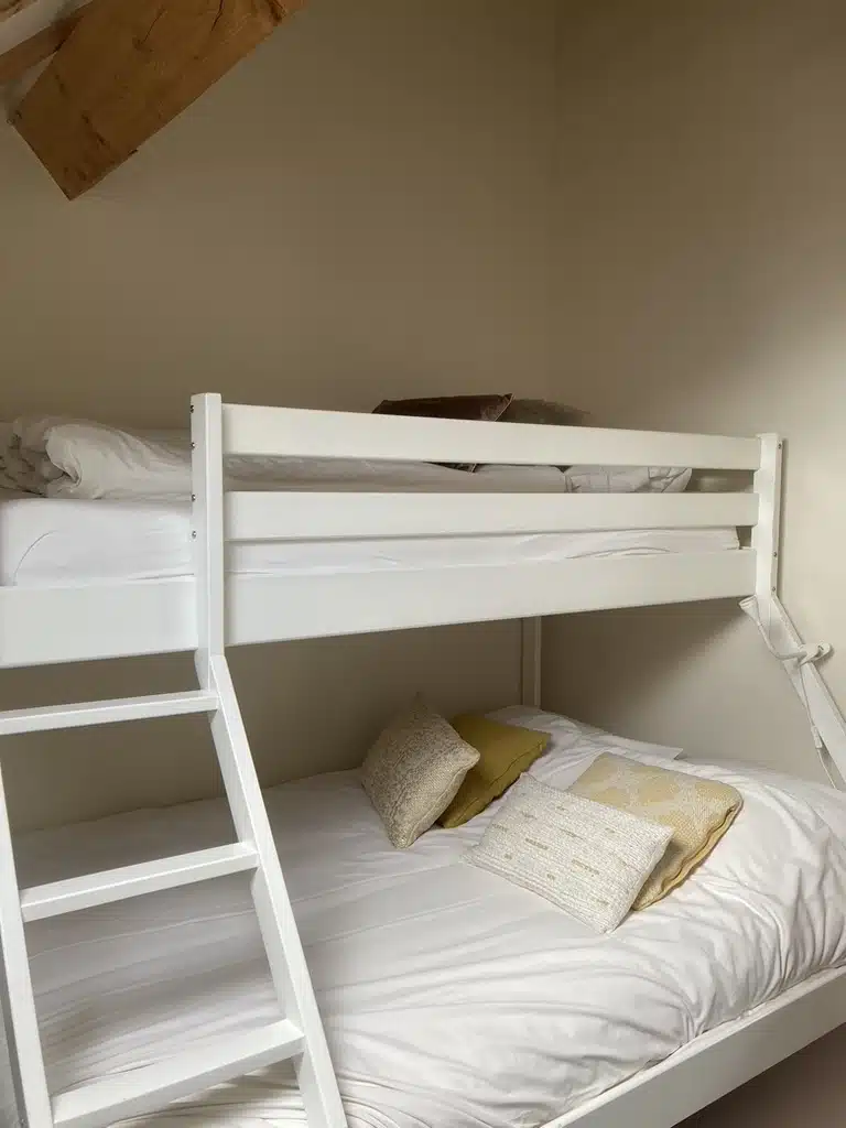 Witte stapelbed met ladder en gele sierkussens op het onderbed, slaapkamer bij vakantieverblijf Eyndevelde